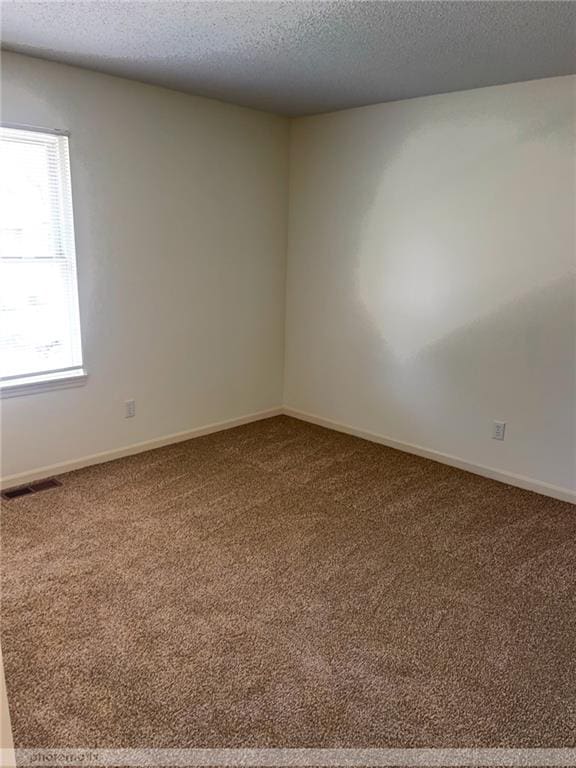 carpeted empty room with a textured ceiling