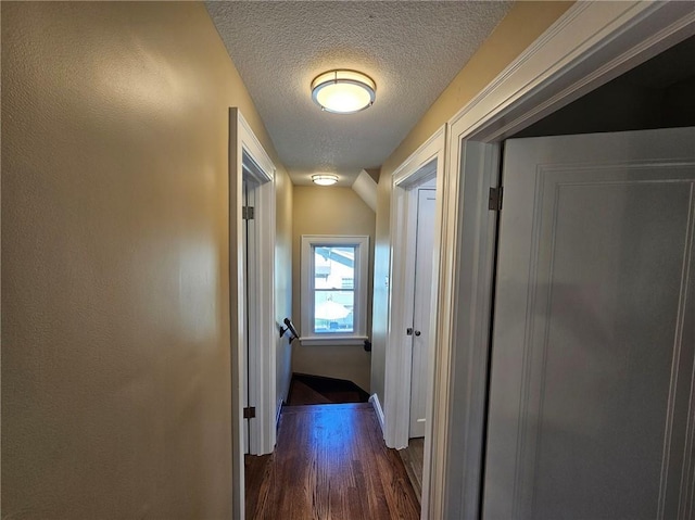 corridor featuring a textured ceiling and dark hardwood / wood-style floors