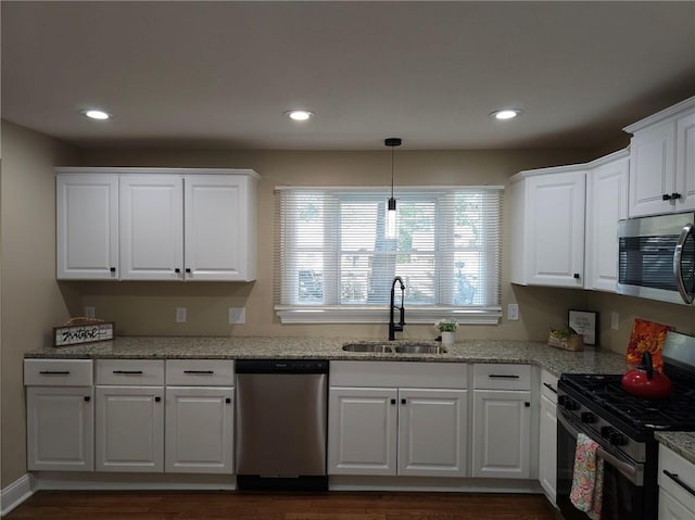 kitchen with white cabinets, appliances with stainless steel finishes, dark hardwood / wood-style floors, and sink