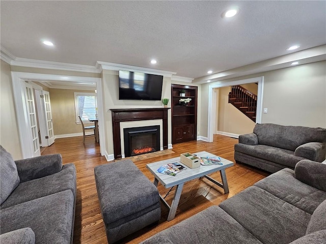 living room with a textured ceiling, crown molding, and hardwood / wood-style flooring