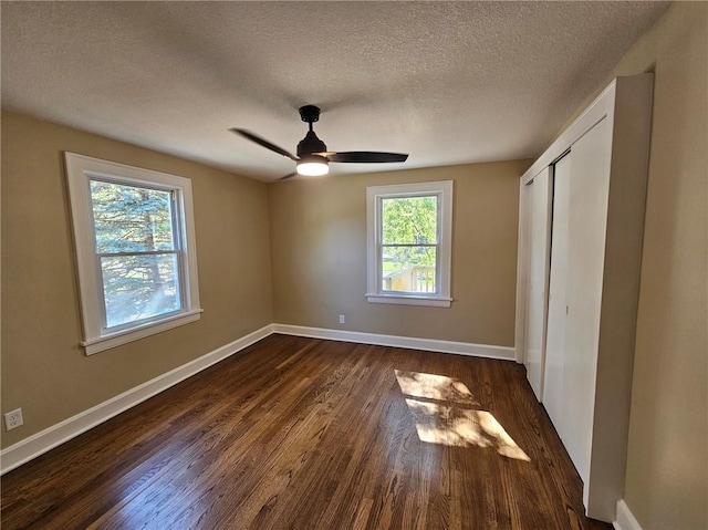 unfurnished bedroom with ceiling fan, a textured ceiling, a closet, and dark hardwood / wood-style flooring