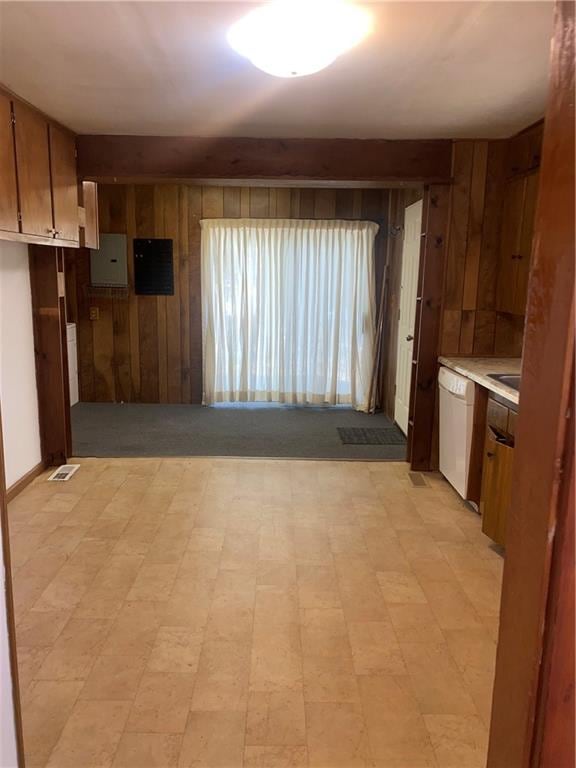 kitchen with dishwasher, wooden walls, and electric panel