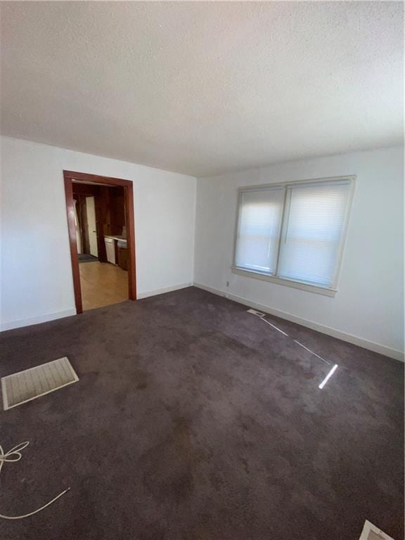 empty room featuring dark colored carpet and a textured ceiling