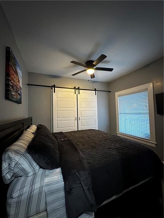 bedroom with a barn door and ceiling fan