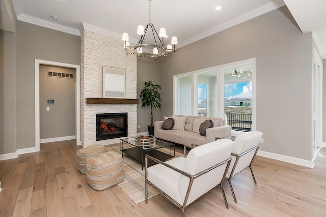 living room featuring an inviting chandelier, crown molding, a fireplace, and light wood-type flooring