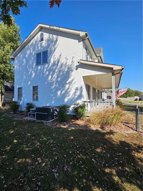 view of side of property with a lawn, covered porch, and central AC