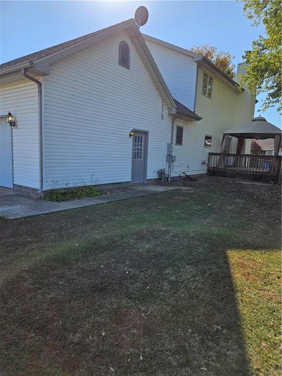 rear view of property with a garage, a gazebo, and a lawn