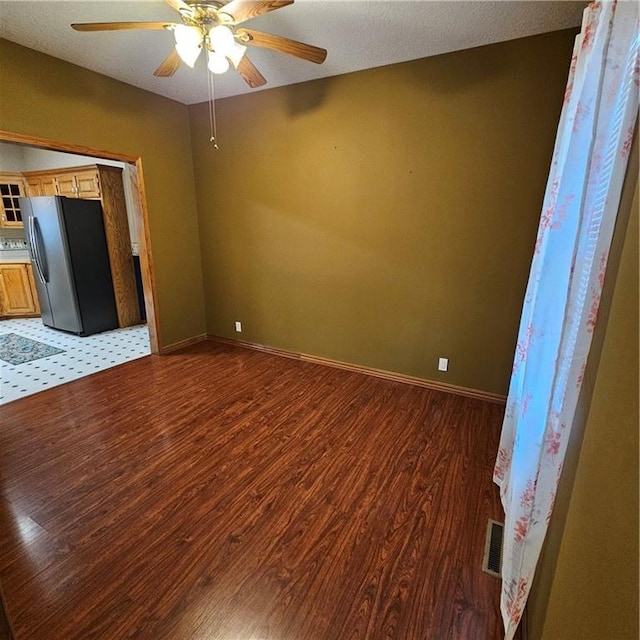 unfurnished room featuring ceiling fan, dark wood-type flooring, and a textured ceiling