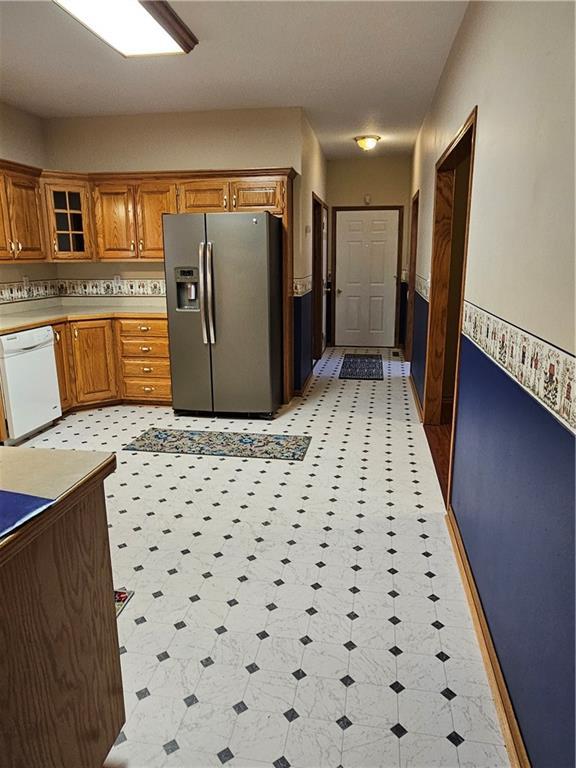 2007 Windsor Dr, Pittsburg, KS 66762 - kitchen with light floors, brown cabinetry, light countertops, dishwasher, and stainless steel refrigerator with ice dispenser