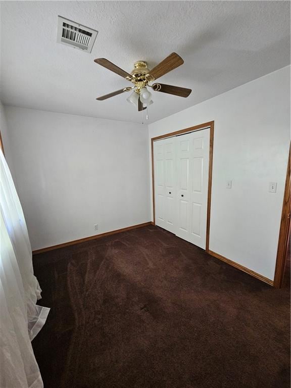 unfurnished bedroom with ceiling fan, a textured ceiling, a closet, and carpet flooring