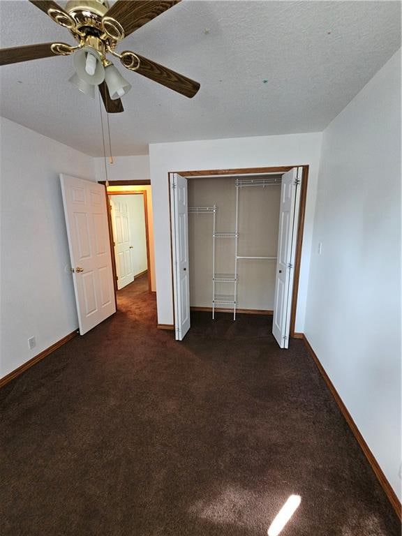 unfurnished bedroom with a closet, dark colored carpet, ceiling fan, and a textured ceiling