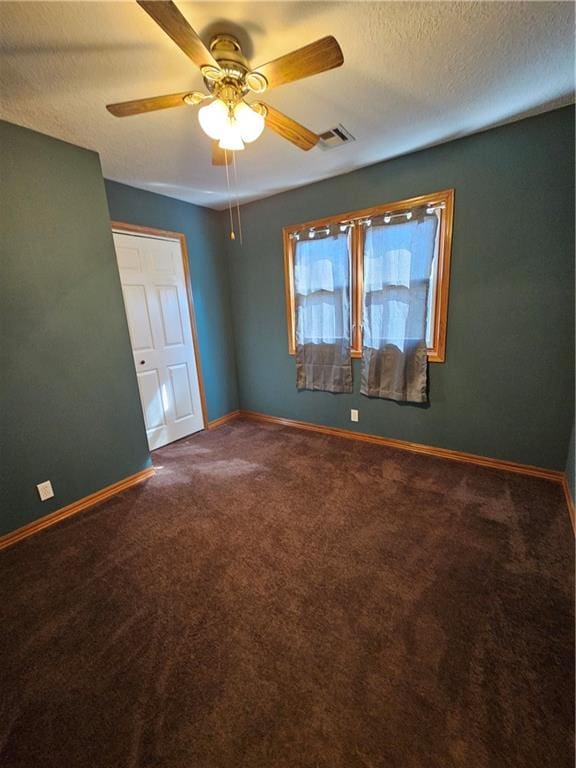 carpeted spare room with a textured ceiling and ceiling fan