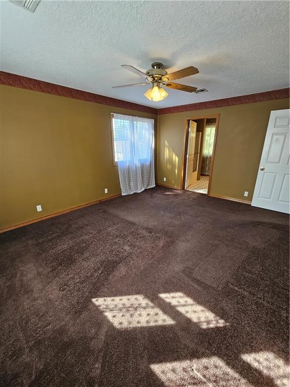 carpeted spare room with ceiling fan and a textured ceiling