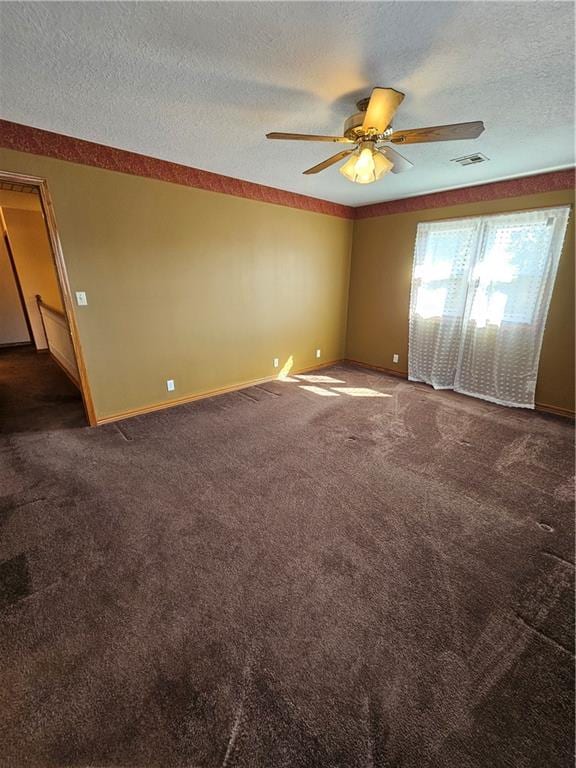 carpeted empty room with ceiling fan and a textured ceiling