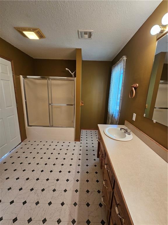 bathroom with a textured ceiling, a shower with door, and vanity