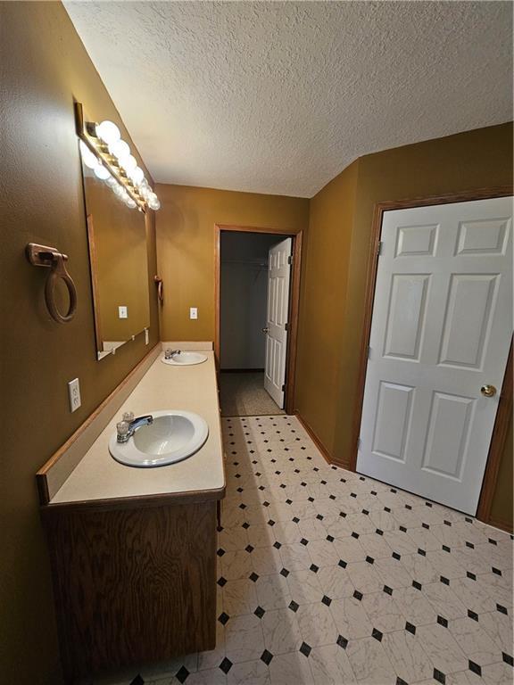 2007 Windsor Dr, Pittsburg, KS 66762 - bathroom with tile patterned floors, a textured ceiling, double vanity, and a sink