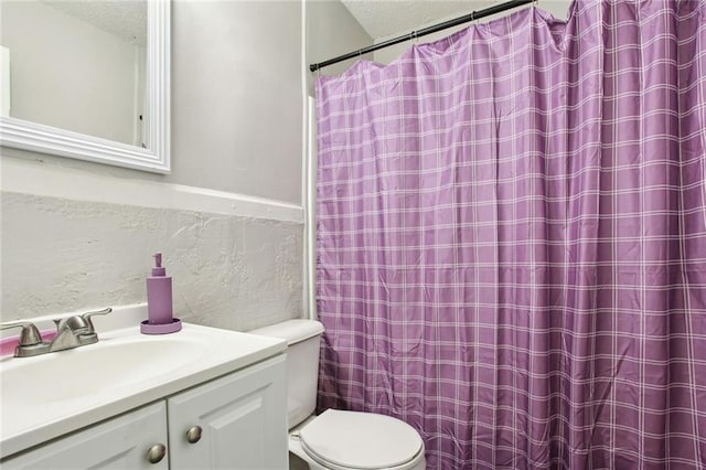 bathroom with a shower with curtain, vanity, toilet, and a textured ceiling