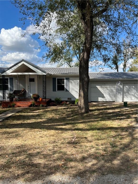 ranch-style home featuring a front lawn, covered porch, and a garage