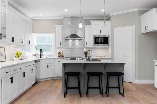 31409 W 85th Ter, De Soto, KS 66018 - kitchen with built in microwave, white cabinets, a sink, wall chimney exhaust hood, and a kitchen bar