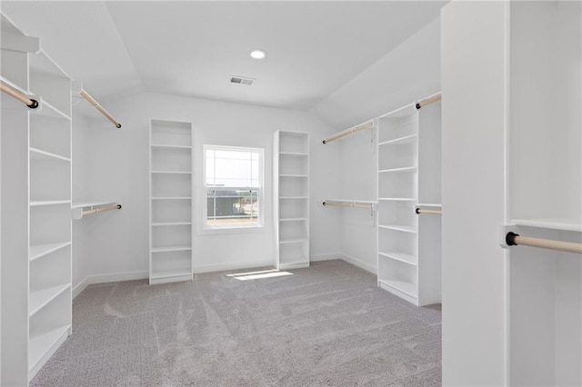 walk in closet with vaulted ceiling and light carpet