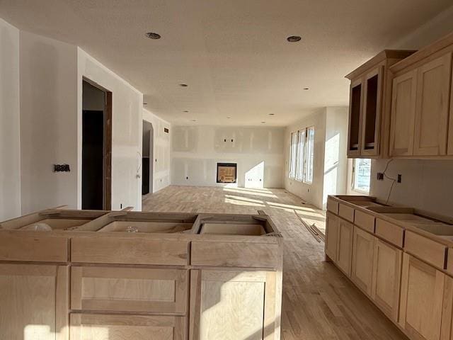 kitchen featuring light brown cabinetry, a fireplace, light hardwood / wood-style floors, and a center island