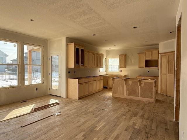 kitchen featuring light wood-type flooring, a center island, a textured ceiling, and light brown cabinets