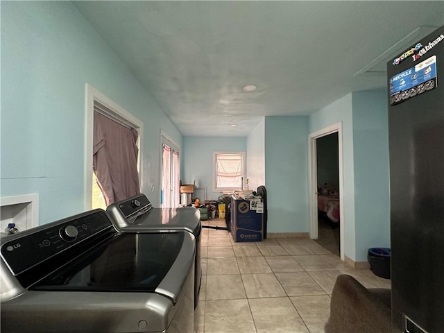 laundry room with light tile patterned flooring, washer and dryer, and a wealth of natural light