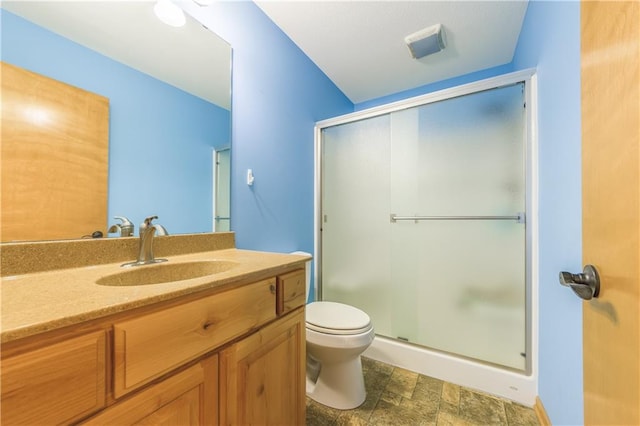 bathroom with toilet, vanity, and a shower with door