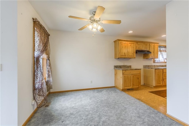 kitchen featuring light brown cabinetry, ceiling fan, and light carpet