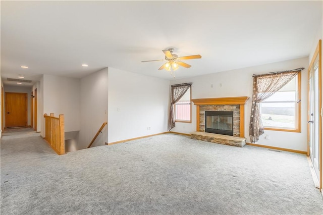 unfurnished living room with a stone fireplace, light colored carpet, and ceiling fan