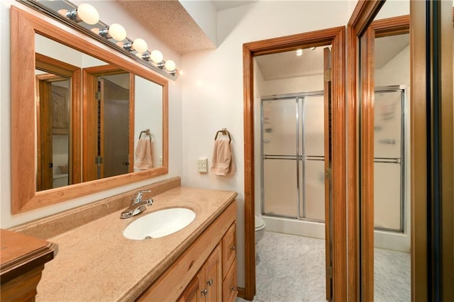 bathroom featuring vanity, toilet, and a shower with shower door