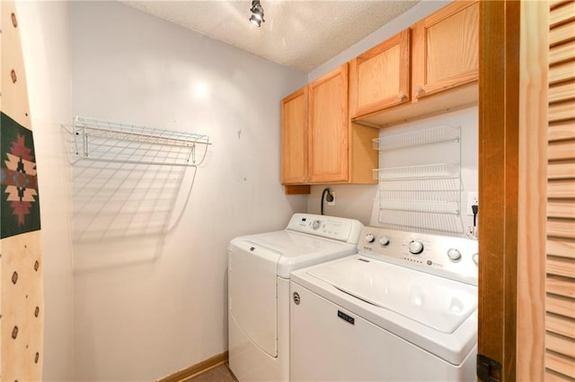 laundry room with washer and dryer, a textured ceiling, and cabinets