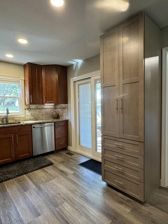 kitchen featuring decorative backsplash, wood-type flooring, sink, and stainless steel dishwasher