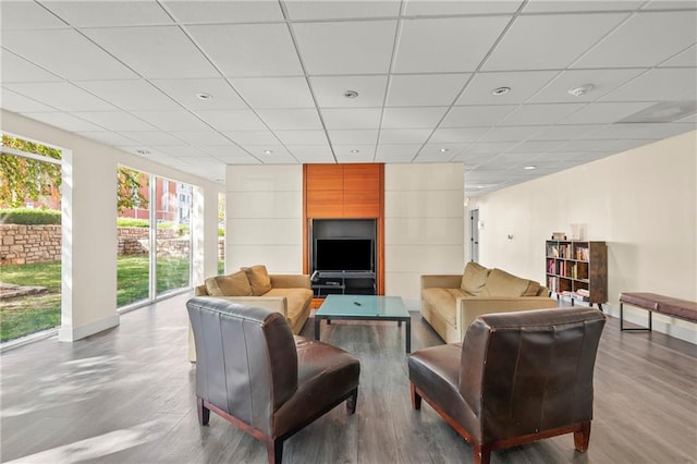 living room featuring wood-type flooring and a drop ceiling