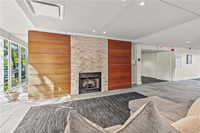 living room featuring wood walls and a stone fireplace