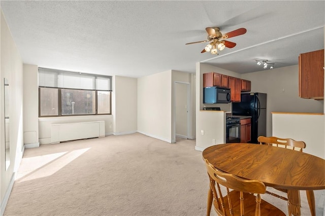 kitchen with a textured ceiling, black appliances, radiator, and light colored carpet