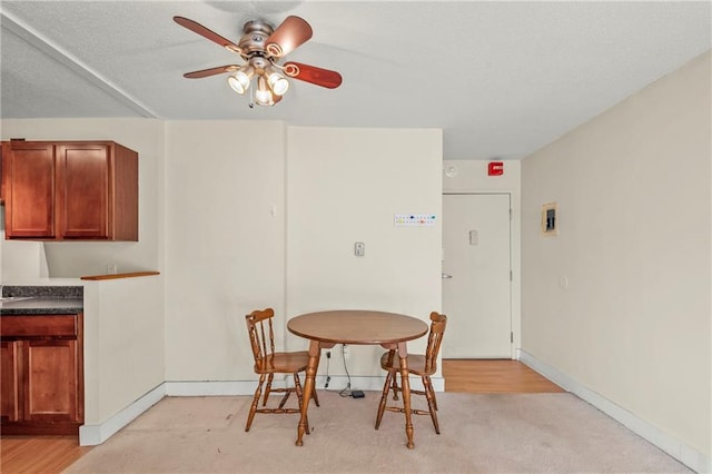 dining space with light carpet and ceiling fan