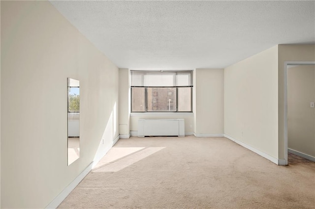 unfurnished room with light carpet, radiator heating unit, and a textured ceiling