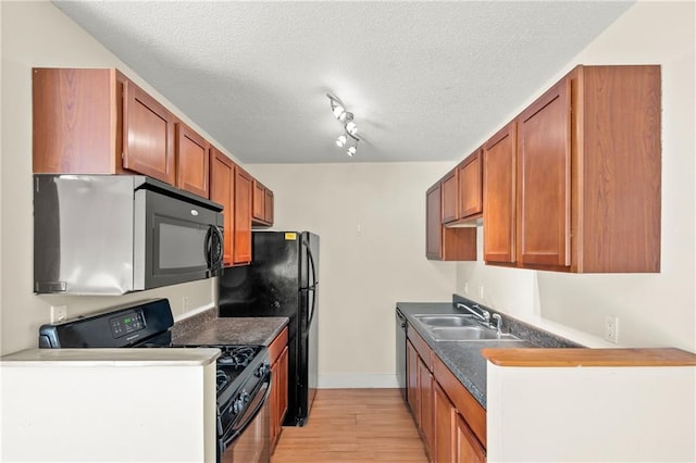 kitchen featuring light wood-type flooring, black appliances, sink, and a textured ceiling