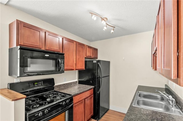 kitchen featuring a textured ceiling, light wood-type flooring, sink, and black appliances