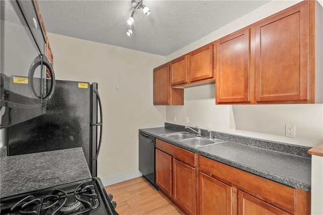 kitchen featuring black appliances, sink, light hardwood / wood-style floors, and a textured ceiling