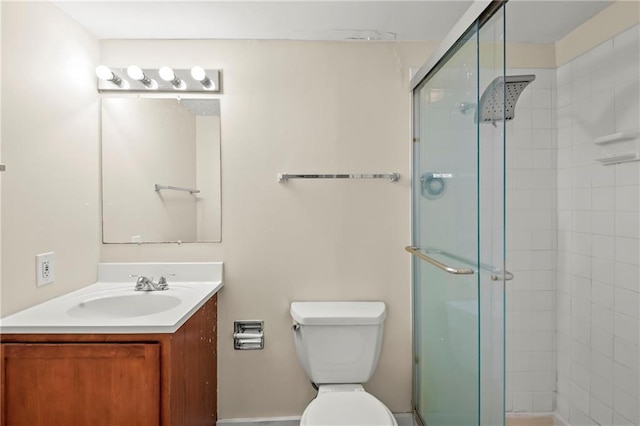 bathroom featuring vanity, a shower with shower door, and toilet