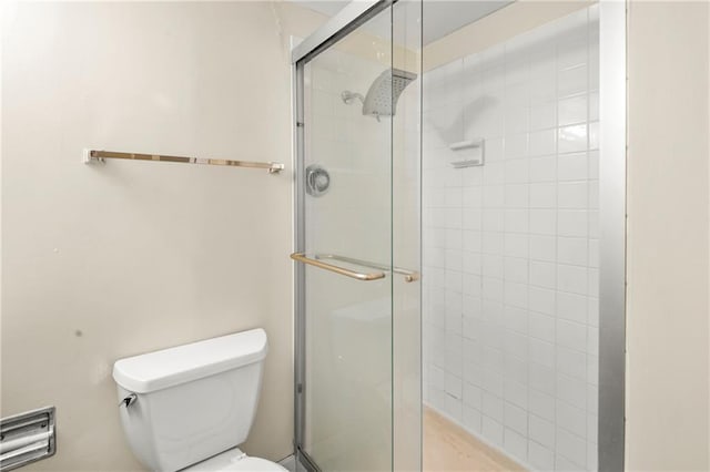 bathroom with toilet and a shower with door