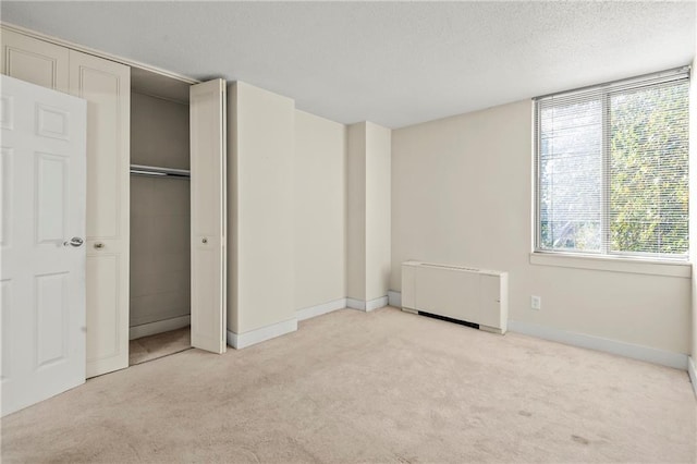 unfurnished bedroom featuring light colored carpet, a textured ceiling, and a closet