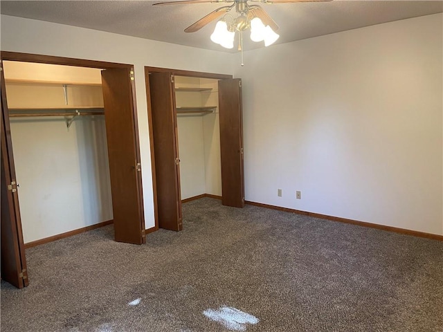 unfurnished bedroom with ceiling fan, multiple closets, and dark colored carpet