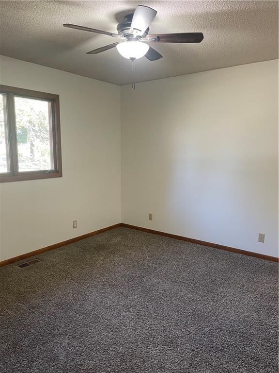 unfurnished room with a textured ceiling, ceiling fan, and carpet flooring