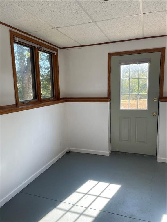 interior space with a paneled ceiling, a wealth of natural light, and concrete flooring