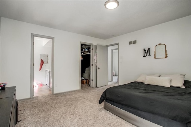 carpeted bedroom featuring ensuite bathroom, a closet, and a walk in closet