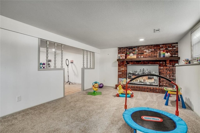 game room with a brick fireplace, carpet, and a textured ceiling