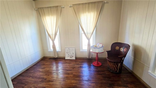 living area featuring dark wood-type flooring and wood walls